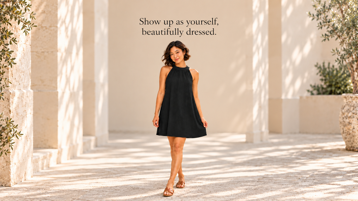 Model wearing the black Textured Grecian Mini Dress beneath the message Show up as yourself, beautifully dressed.